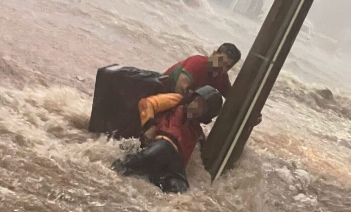 Carmo do Paranaíba - Pessoas se seguram em poste para não serem arrastadas pela correnteza durante temporal na cidade